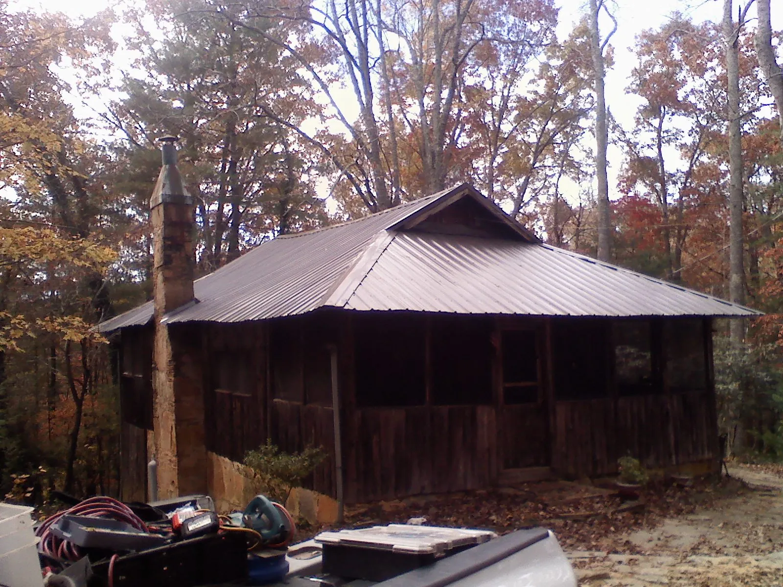 Brown metal hip roof on an old cabin with a stone chimney in Pulaski